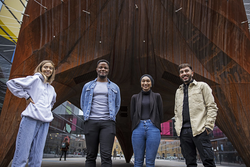 Four students standing together, smiling