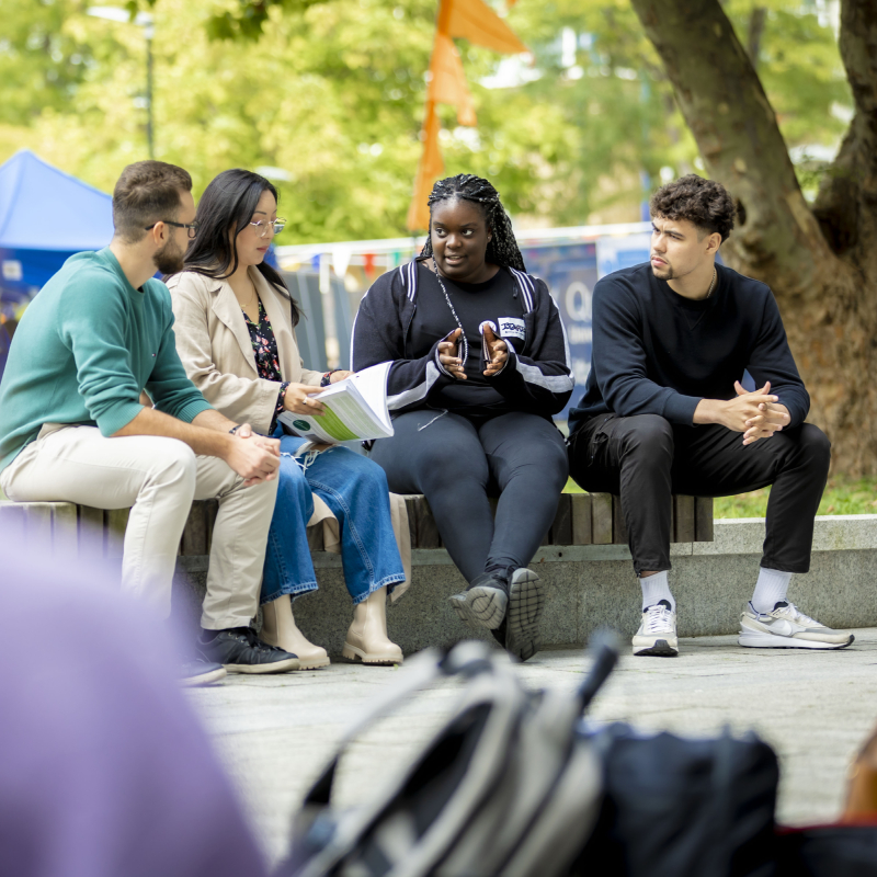 Students sitting on a wall and talking at the Mile End campus