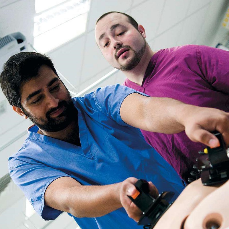 Medicine students in coloured scrubs practising clinical skills