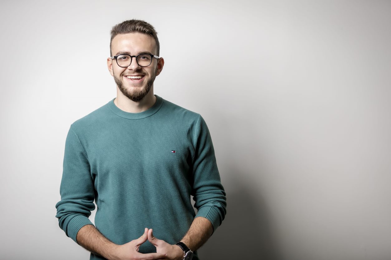 A student in a turquoise jumper smiling at the camera